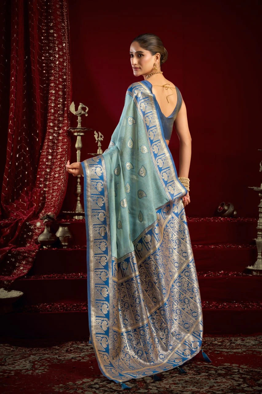 Woman wearing a traditional saree with a blue and gold pattern in a decorative setting.